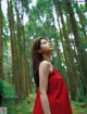 A woman in a red dress standing in a forest.