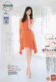 A woman in an orange dress posing for a magazine.