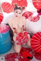 A naked asian woman sitting on a bed with red paper lanterns.