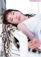 A woman laying on a white chair with a blanket over her head.