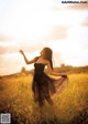 A woman in a black dress standing in a field.