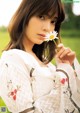 A woman holding a flower in her hand in a field.