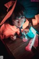 A little girl in a witches hat and glasses sitting at a table.