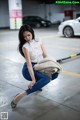 A woman crouching down in a parking garage holding a blanket.