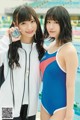 A couple of young women standing next to each other near a swimming pool.