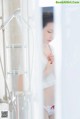 A woman standing in front of a shower in a bathroom.