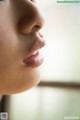 A close up of a woman's face looking out a window.