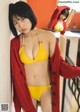 A woman in a yellow bikini and a red cardigan.