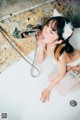 A woman in a bathtub with a cat ears on her head.